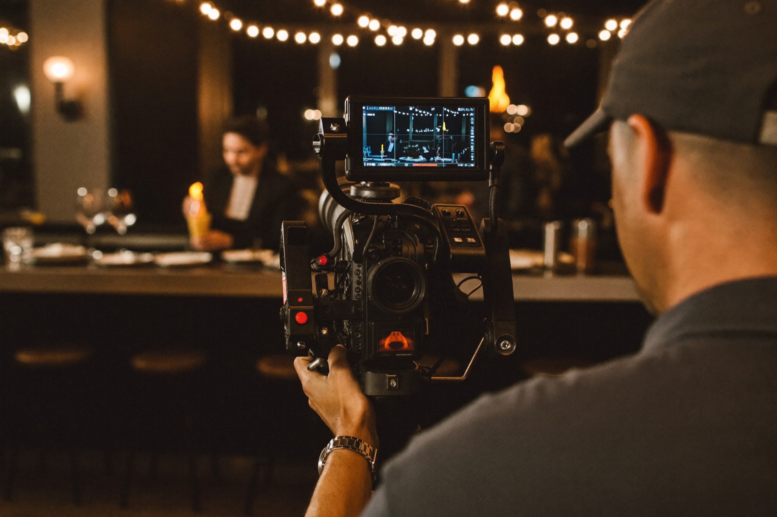 Videographer filming a bartender with a gimbal rig in a moody bar