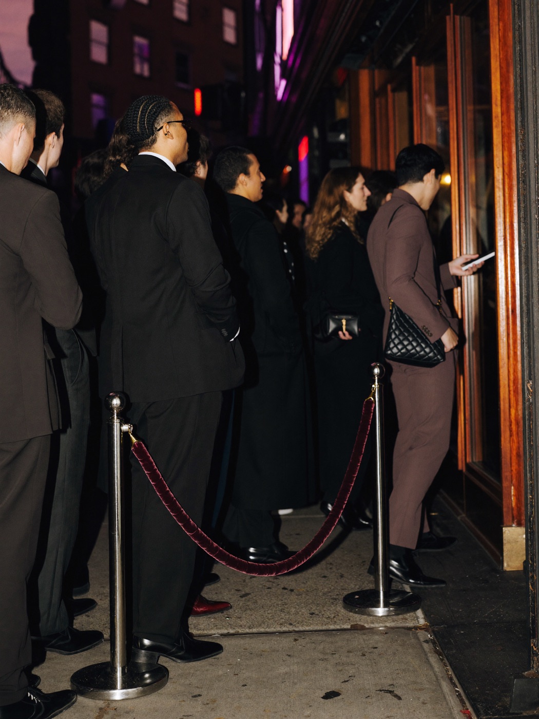 Line of guests outside a glowing venue entrance at night